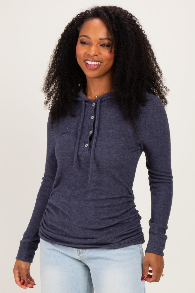 woman wearing a navy blue long sleeve hooded henley top with button details, styled with light wash jeans