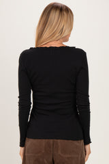 woman wearing a black long sleeve ribbed top with a scalloped neckline and fitted silhouette