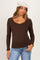 woman wearing a brown ribbed maternity top with a scalloped neckline and long sleeves