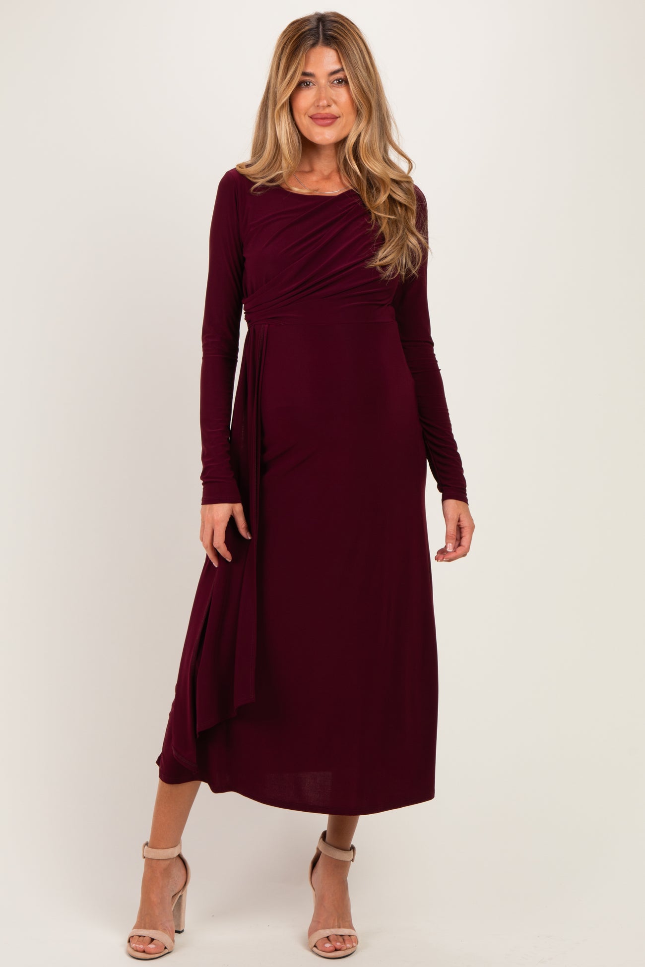 woman wearing a burgundy long sleeve maternity dress with a wrap design and flowing skirt