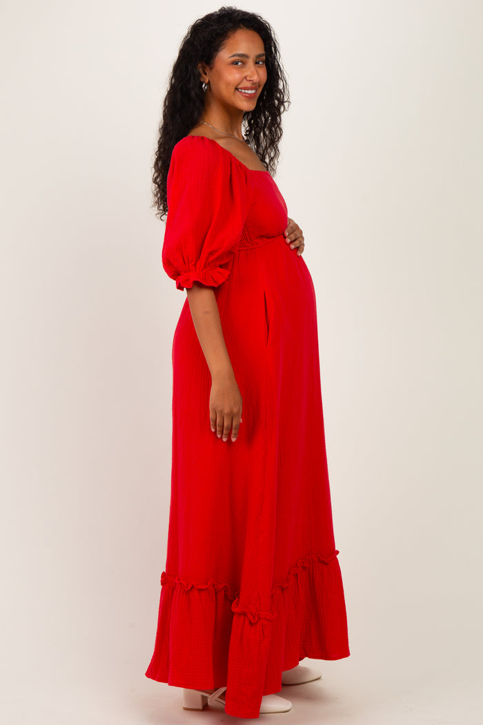 woman wearing a red off-the-shoulder maternity maxi dress with puff sleeves and ruffle hem, showing baby bump