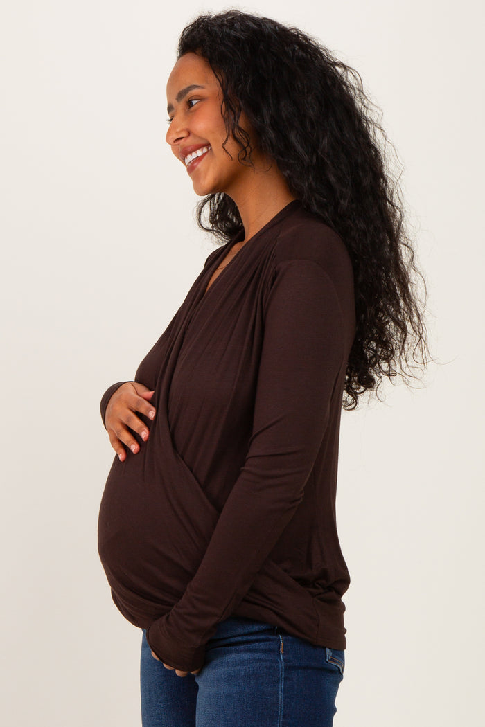 woman wearing a brown maternity wrap top and showing her baby bump while smiling