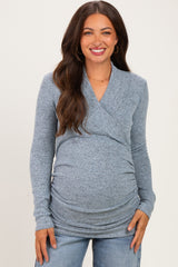 woman wearing a light blue maternity top with a wrap design and long sleeves, showing her baby bump
