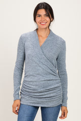 woman wearing a light blue wrap top with side ruching and long sleeves paired with blue jeans