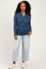 woman wearing a navy blue long sleeve wrap top with gathered detailing and light wash wide leg jeans