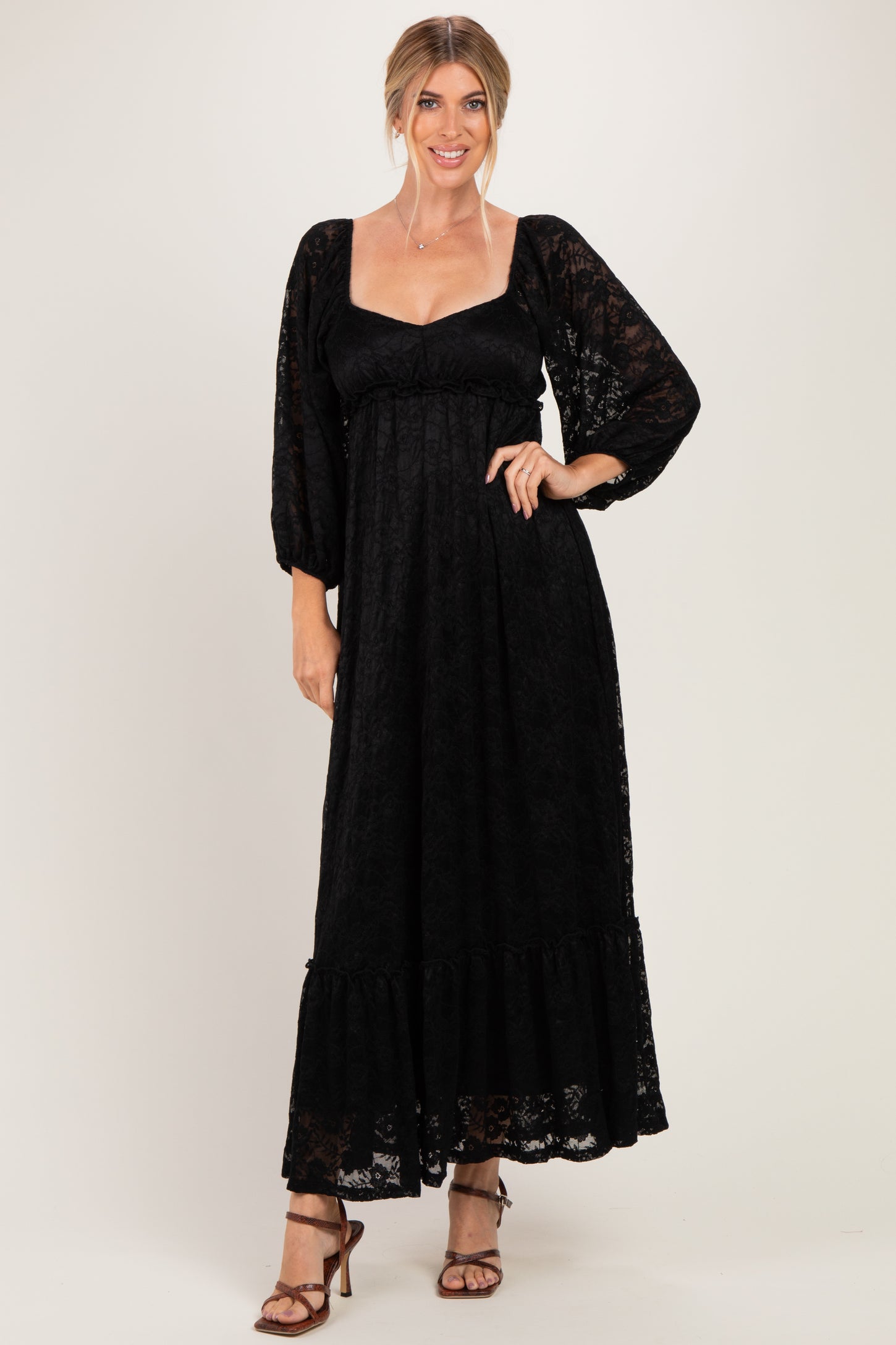woman wearing a black lace maxi dress with long puff sleeves and a ruffled hemline