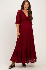 woman wearing a burgundy lace maternity maxi dress with ruffled sleeves and a deep v-neck, showing her baby bump