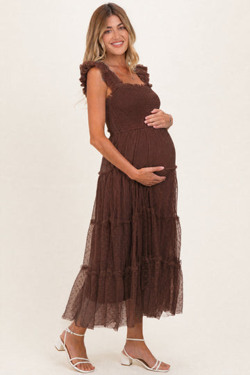 woman wearing a brown tiered maternity dress with ruffle straps and holding her baby bump