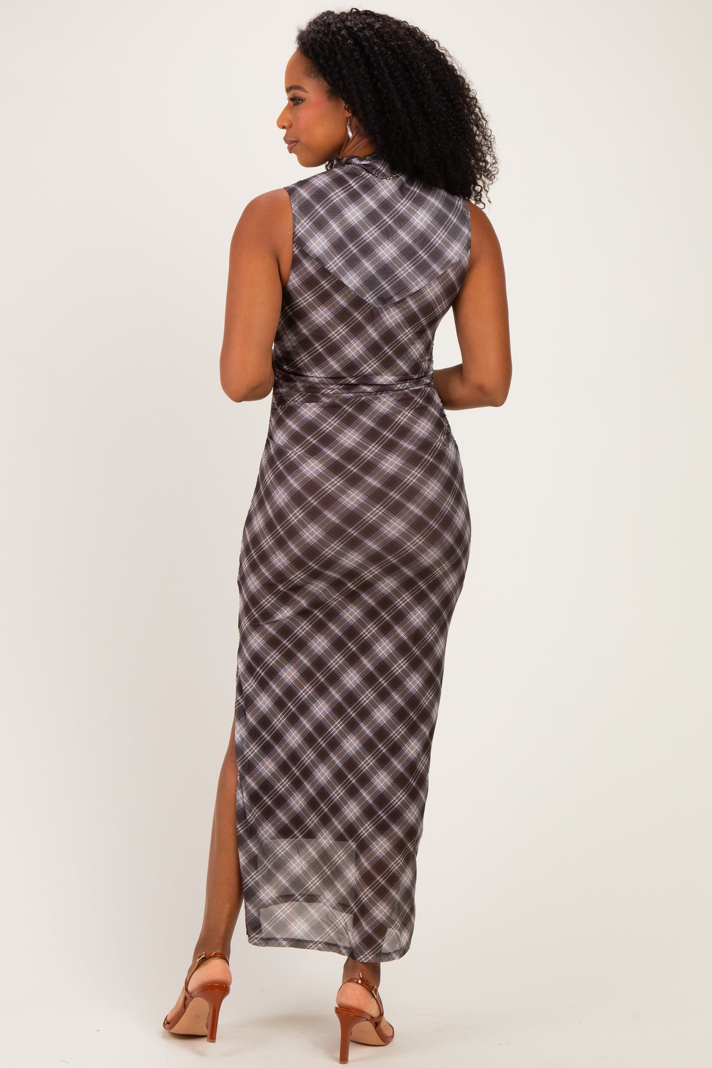 woman wearing a sleeveless plaid maxi dress with a high slit and open back, shown from the back