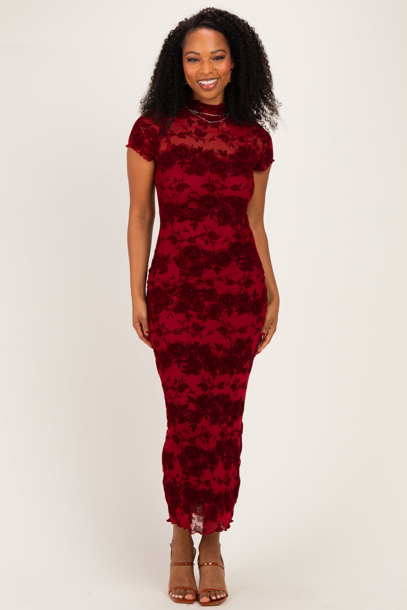 woman wearing a burgundy floral lace evening gown with short sleeves and a fitted silhouette