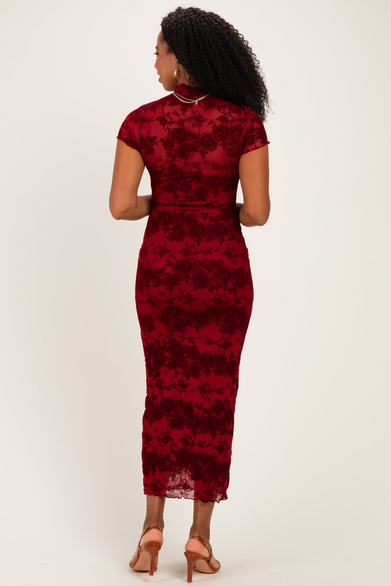 woman wearing a fitted burgundy lace dress with short sleeves and a midi length, showing the back view