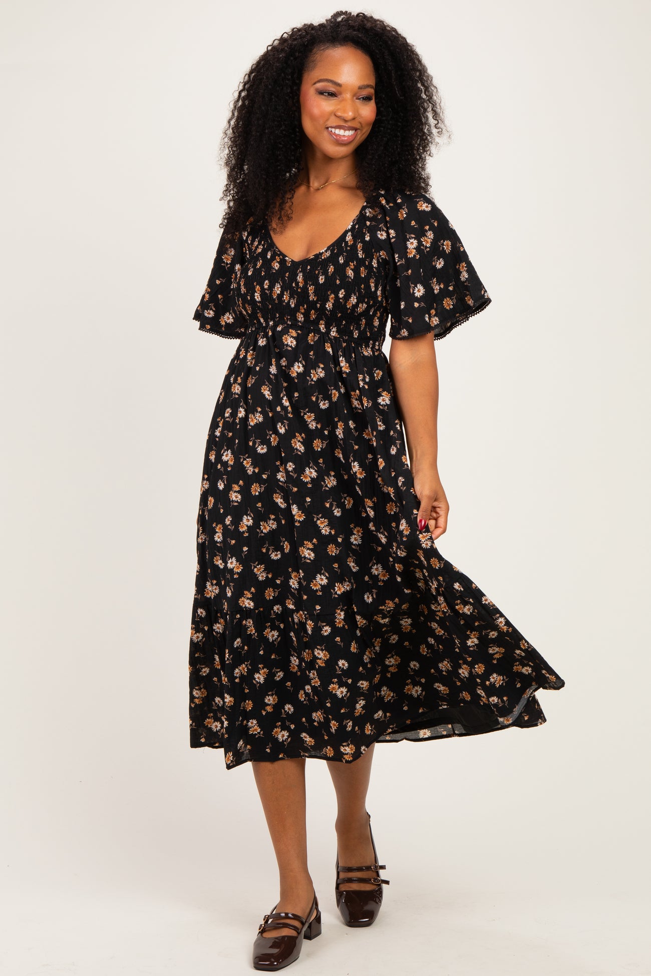 woman wearing a black floral midi dress with puff sleeves and a cinched waist