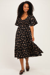 woman wearing a black floral midi dress with puff sleeves and a cinched waist