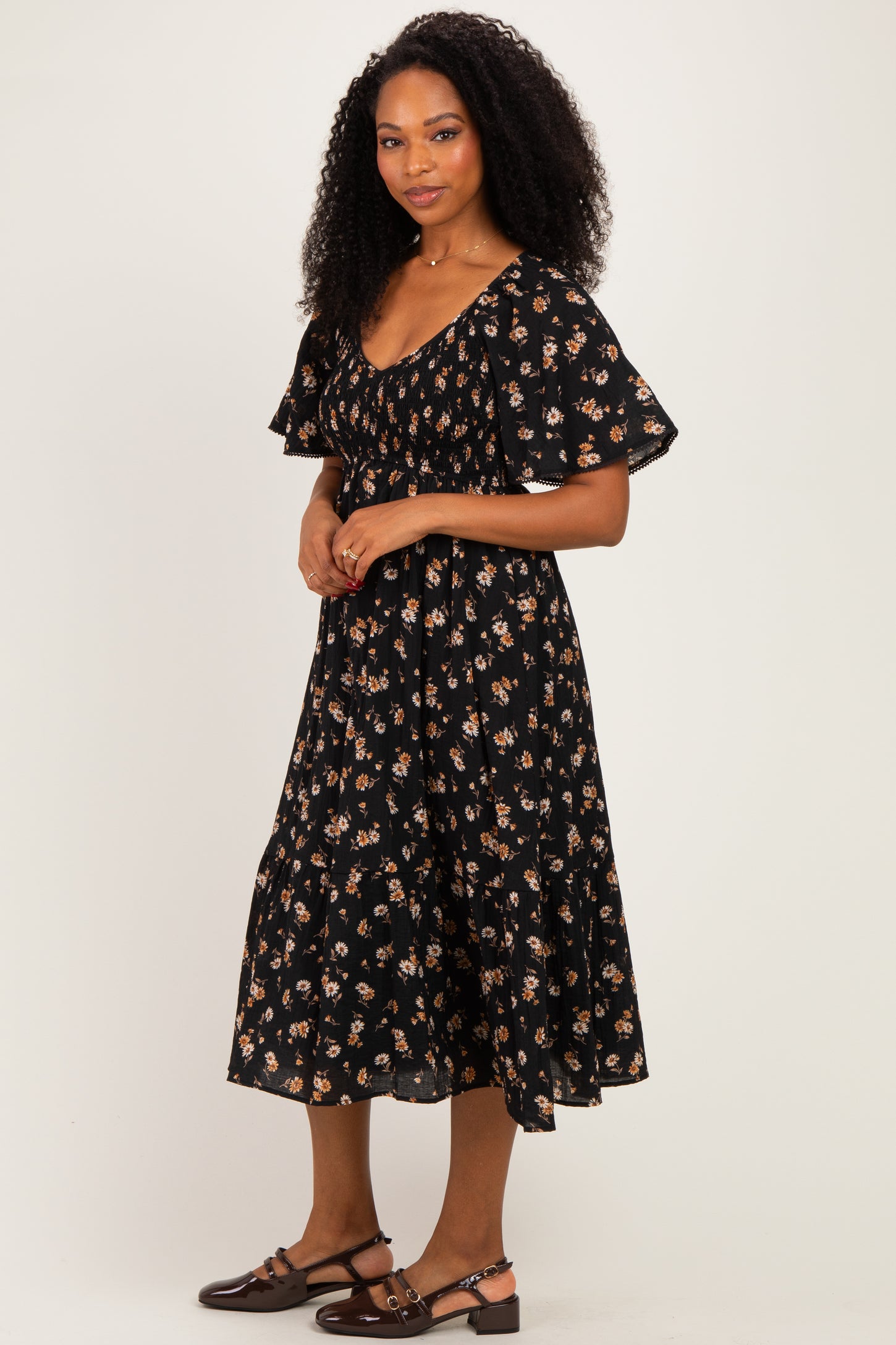 woman wearing a black floral midi dress with puff sleeves and a tiered skirt