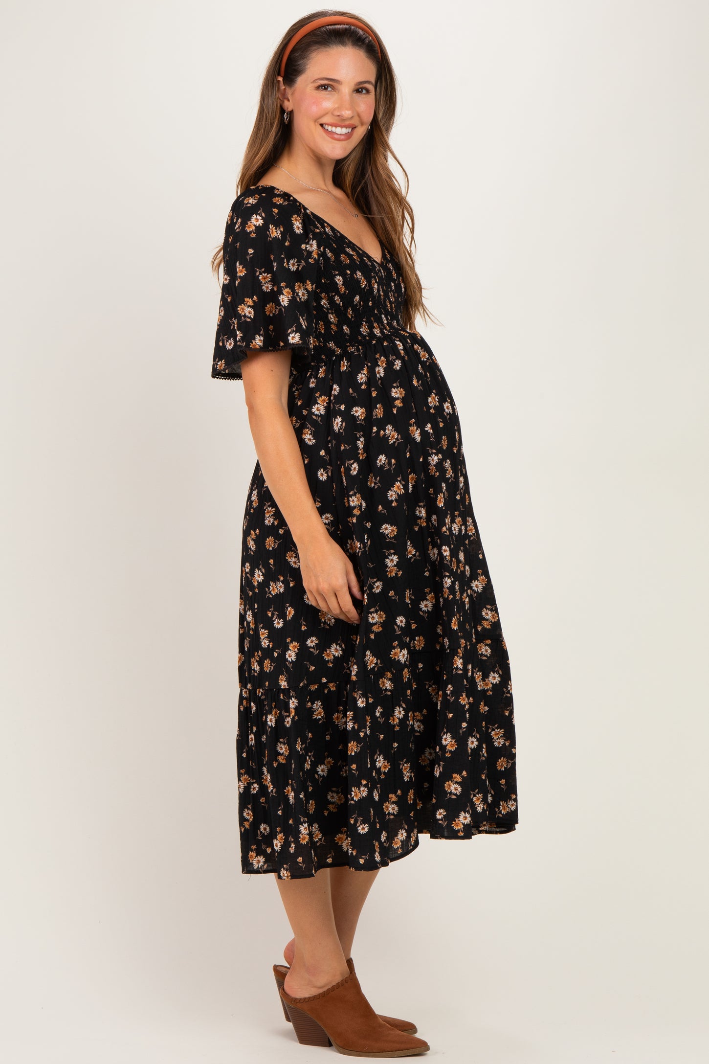 woman wearing a black floral maternity dress with short sleeves and a flowy skirt, accentuating her baby bump