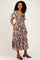 woman wearing a brown floral midi dress with puff sleeves and a square neckline, standing with hands in pockets