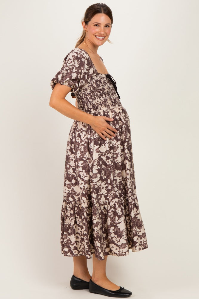 woman wearing a brown and cream floral maternity dress with puff sleeves and a baby bump visible
