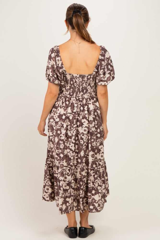 woman wearing a brown and cream floral print maternity dress with short puff sleeves and a smocked bodice