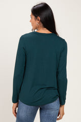 woman wearing a dark teal long sleeve top, viewed from the back, paired with blue jeans