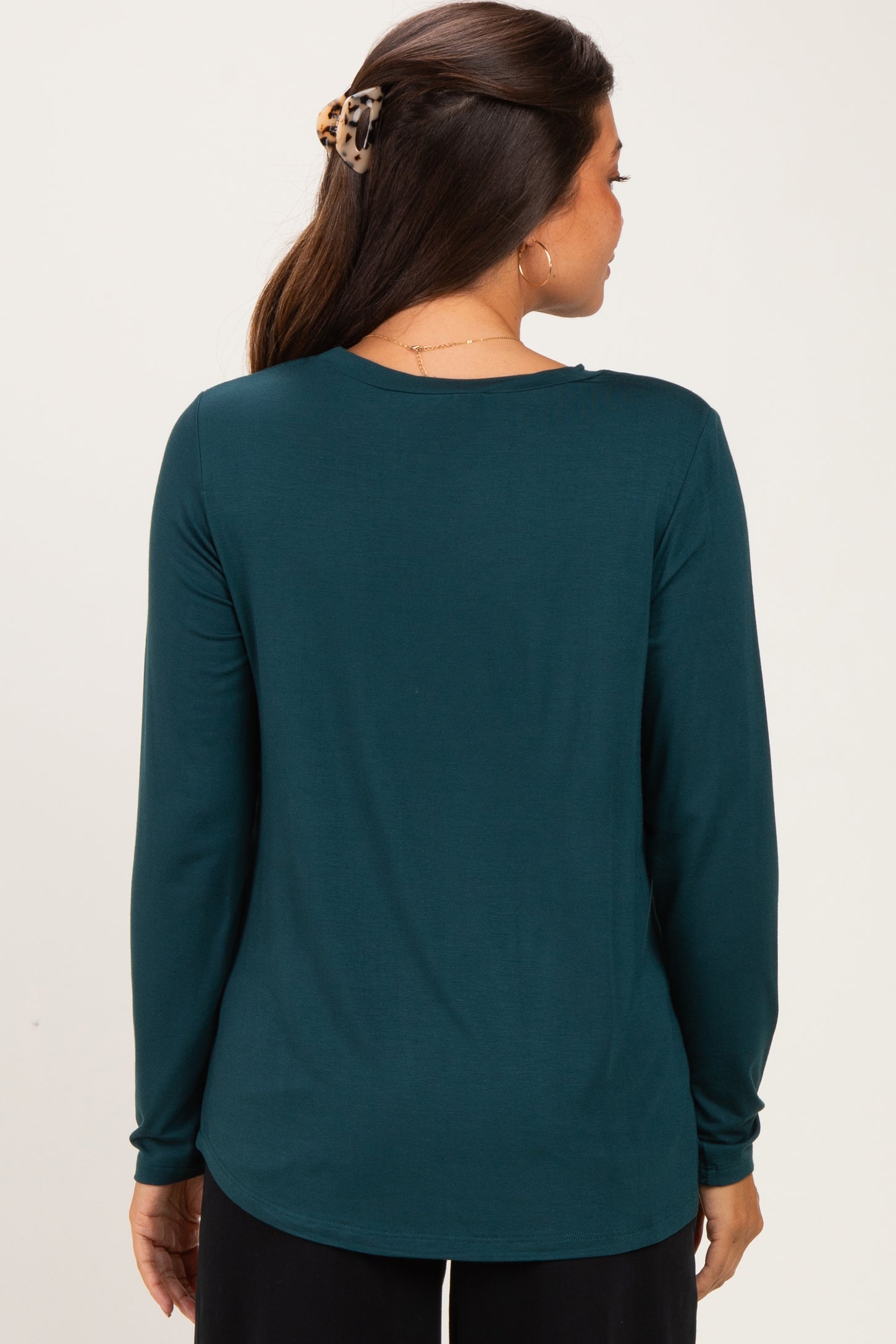 woman wearing a dark teal long sleeve maternity top, showing the back view and a smooth silhouette