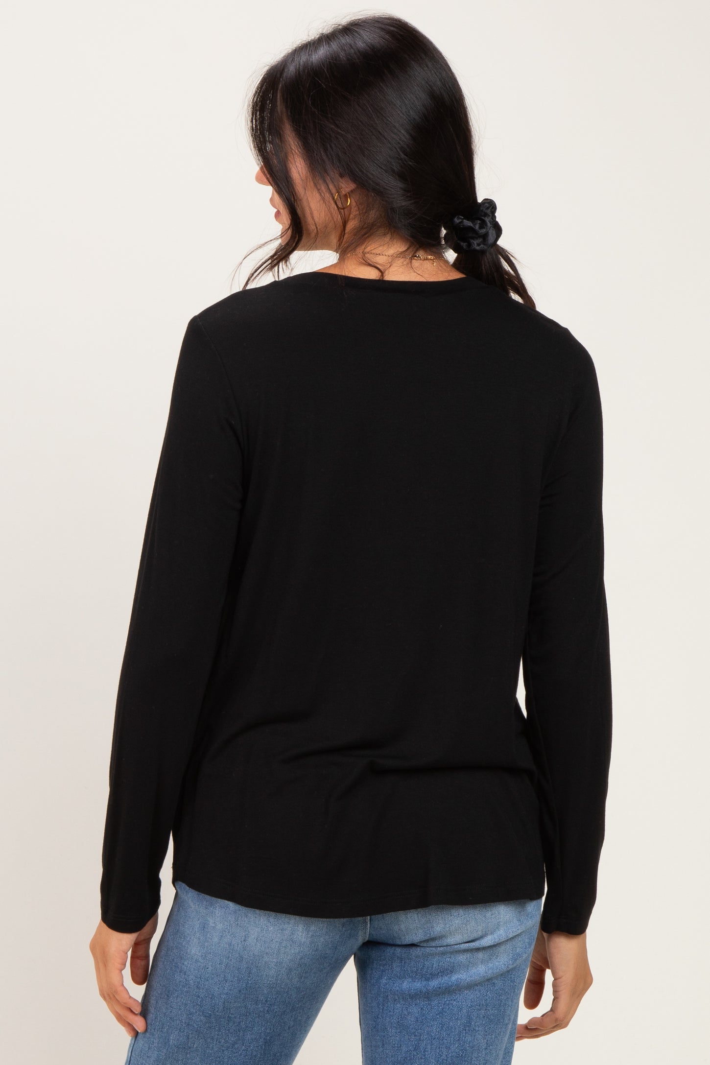 woman wearing a black long sleeve top with a relaxed fit and a round neckline, seen from the back