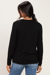 woman wearing a black long sleeve top with a relaxed fit and a round neckline, seen from the back