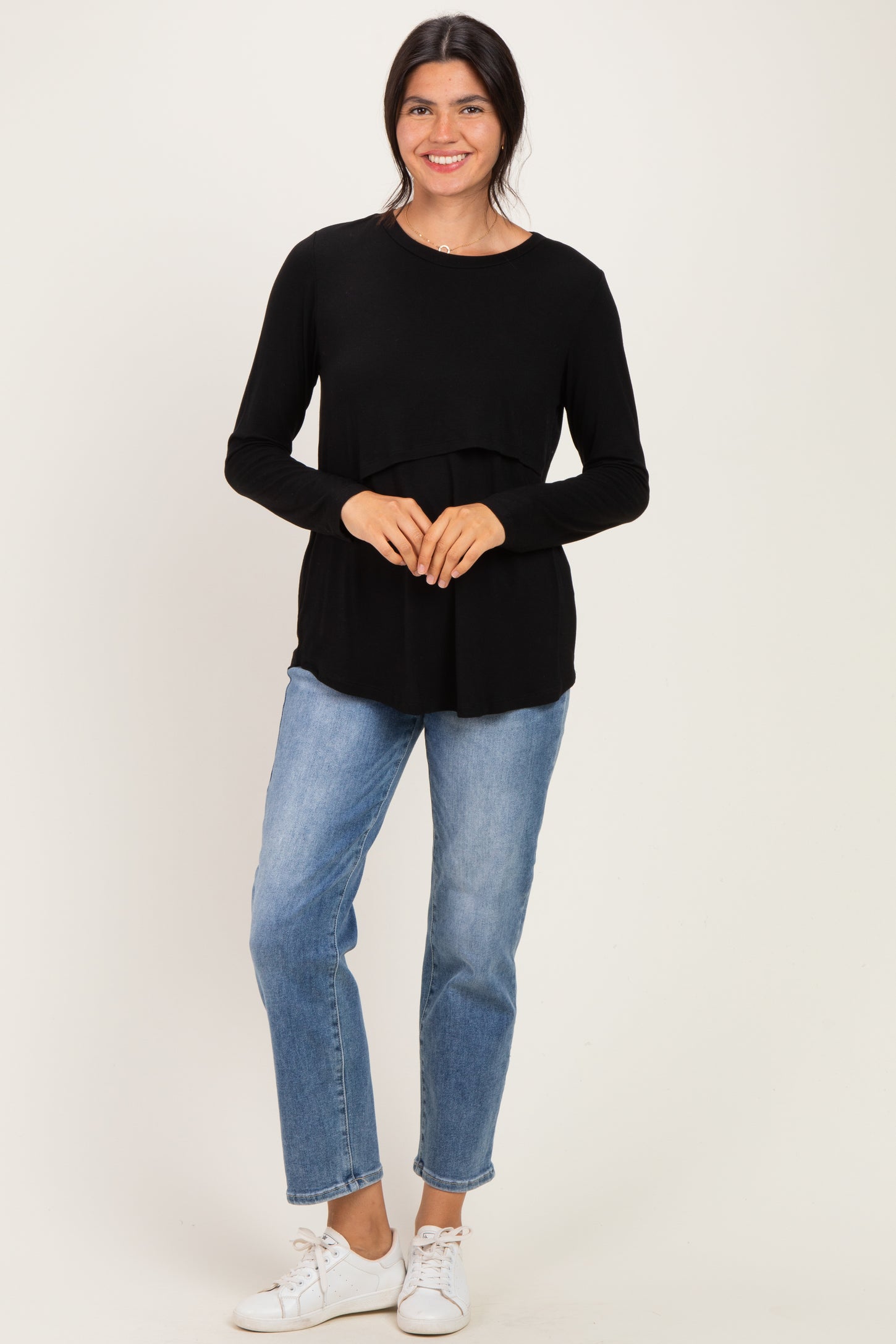 woman wearing a black long sleeve top with a layered design and light blue jeans