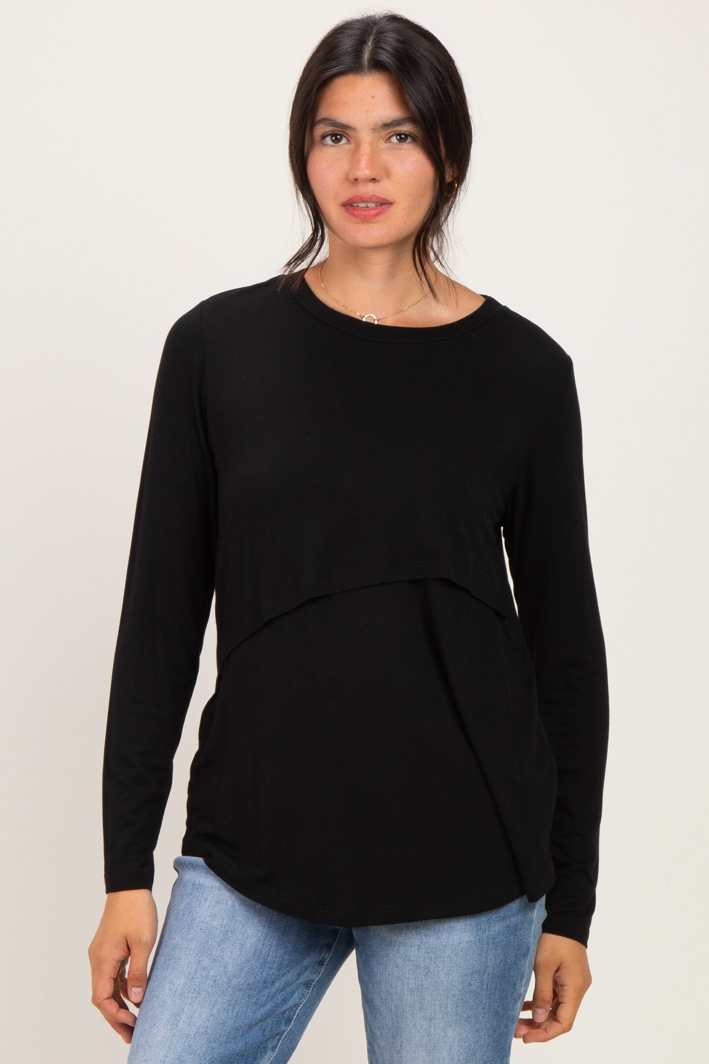 woman wearing a black long sleeve top with a layered design and paired with light blue jeans