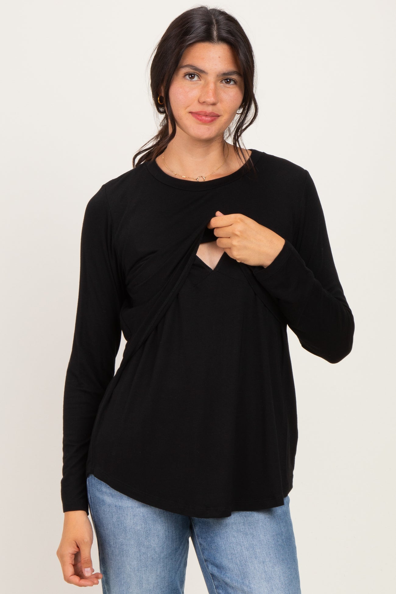 woman wearing a black long sleeve top with a keyhole cutout and layered front detail, styled with light blue jeans