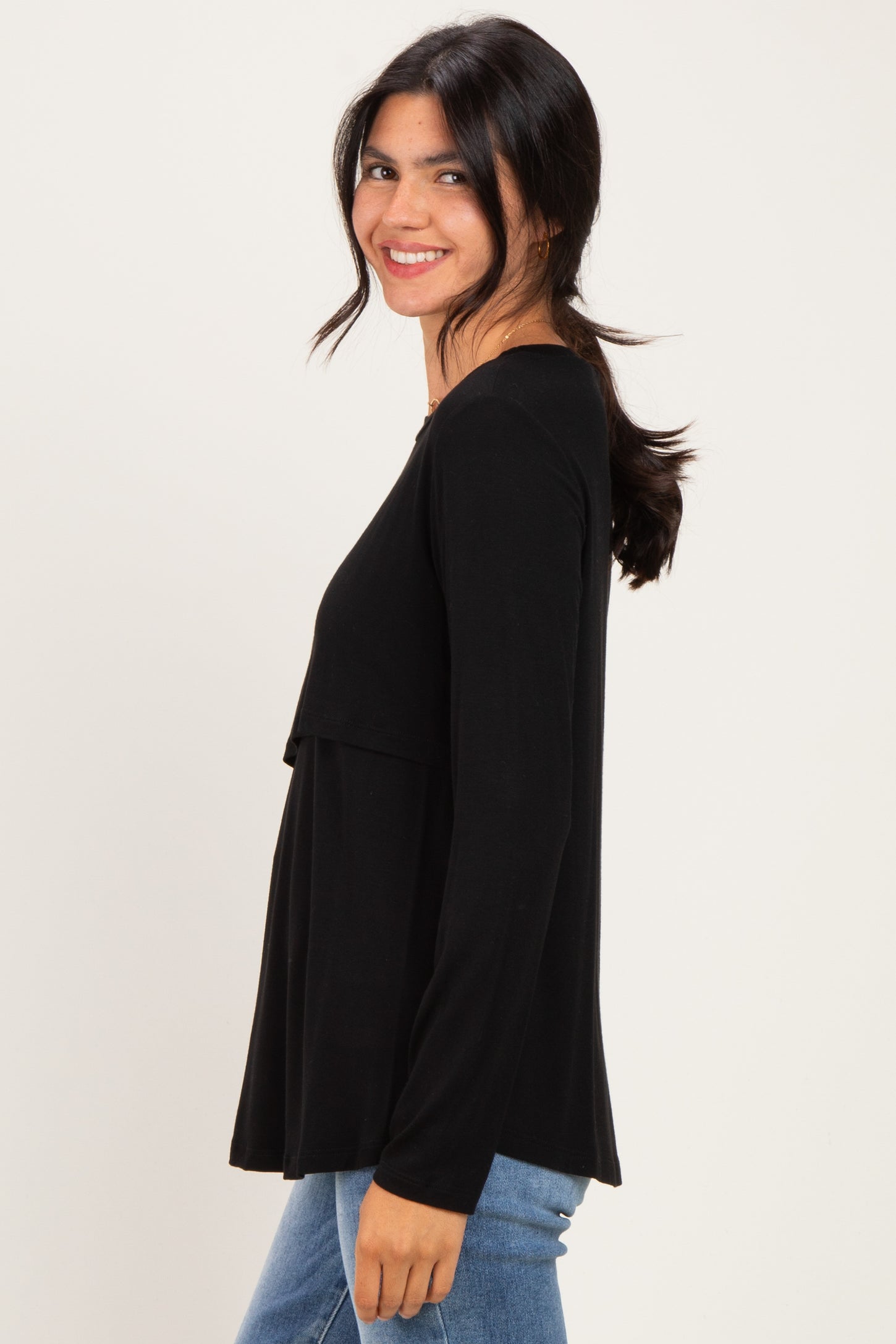 woman wearing a black long sleeve top with a layered design and smiling