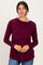 woman wearing a burgundy long sleeve top with a layered design and relaxed fit, posing against a plain background