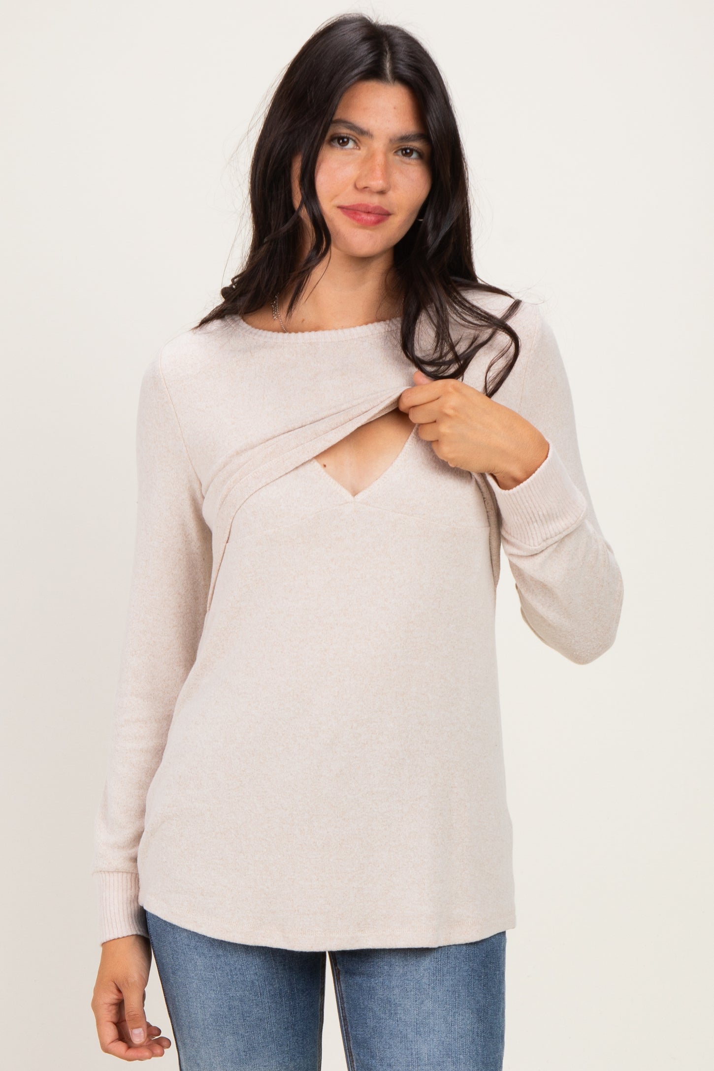 woman wearing a light beige long sleeve sweater with a twist detail at the neckline and a relaxed fit