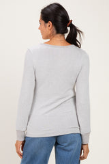 woman wearing a light gray long sleeve sweater, viewed from the back, paired with blue jeans