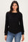 woman wearing a black long sleeve top with a layered design and relaxed fit, paired with blue jeans