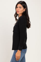 woman wearing a black long sleeve top with a relaxed fit and side view, paired with blue jeans