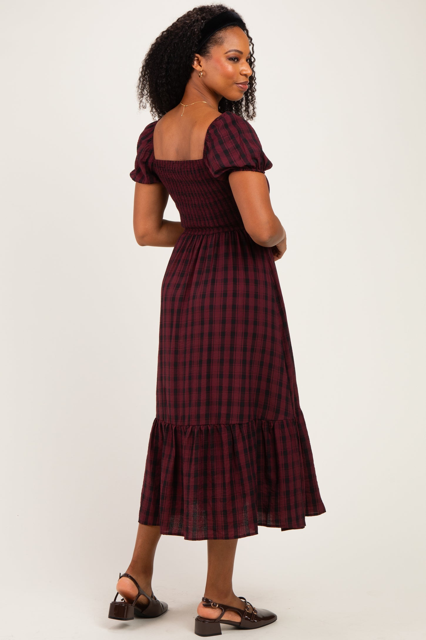 woman wearing a burgundy and black plaid midi dress with puff sleeves and a ruffled hem
