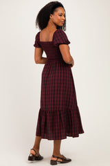 woman wearing a burgundy and black plaid midi dress with puff sleeves and a ruffled hem
