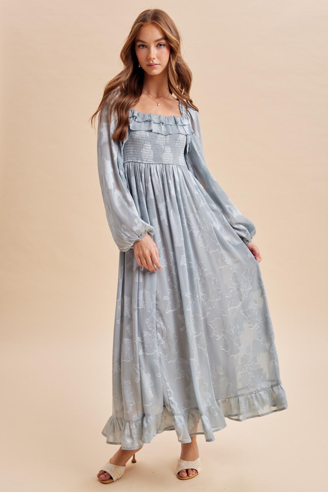 woman wearing a light blue long sleeve maxi dress with ruffle details and a fitted bodice