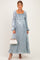 woman wearing a light blue floral maternity maxi dress with long sleeves and a baby bump, holding a handbag