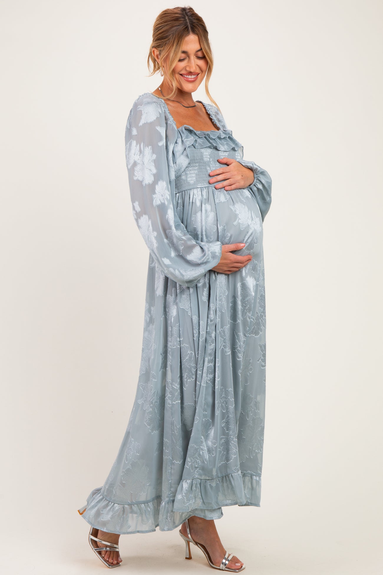 woman wearing a light blue floral maternity maxi dress and holding her baby bump