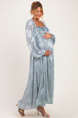 woman wearing a light blue floral maternity maxi dress and holding her baby bump