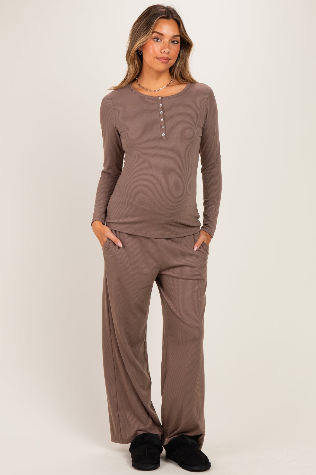 woman wearing a brown maternity long sleeve henley top and matching pants, with a baby bump visible