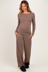woman wearing a brown long sleeve maternity top with buttons and matching wide-leg pants, showing her baby bump