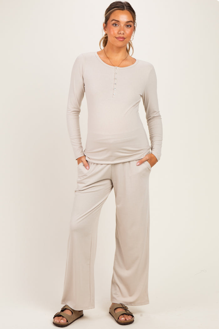 woman wearing a light taupe maternity loungewear set with a long sleeve henley top and wide-leg pants, baby bump visible