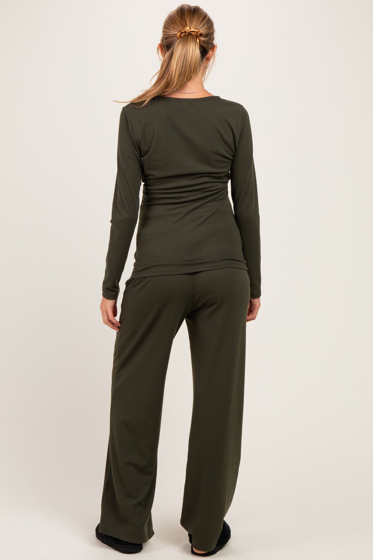 woman wearing an olive green long sleeve maternity top and matching maternity pants, viewed from the back