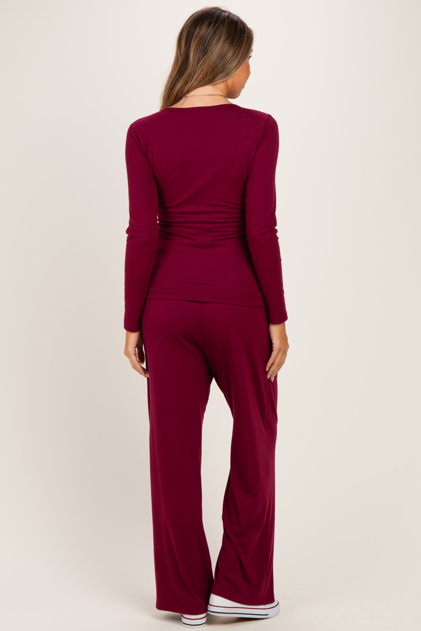 woman wearing a burgundy maternity long sleeve top and matching pants, showing a relaxed fit from the back