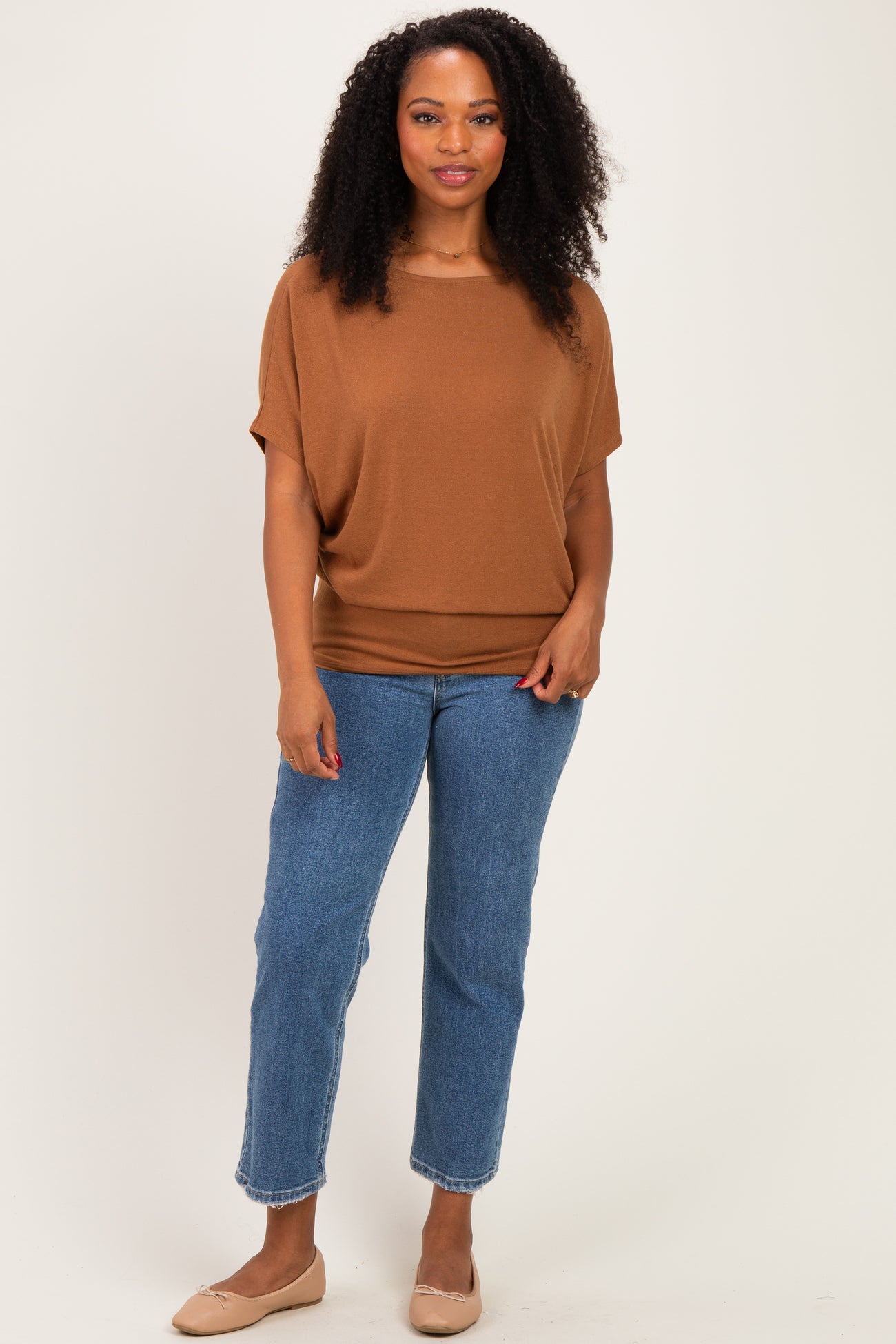 woman wearing a brown short sleeve top with a relaxed fit and blue high-waisted jeans