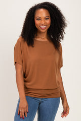 woman wearing a brown short sleeve top with a relaxed fit and smiling at the camera