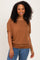 woman wearing a brown short sleeve top with a relaxed fit and smiling at the camera