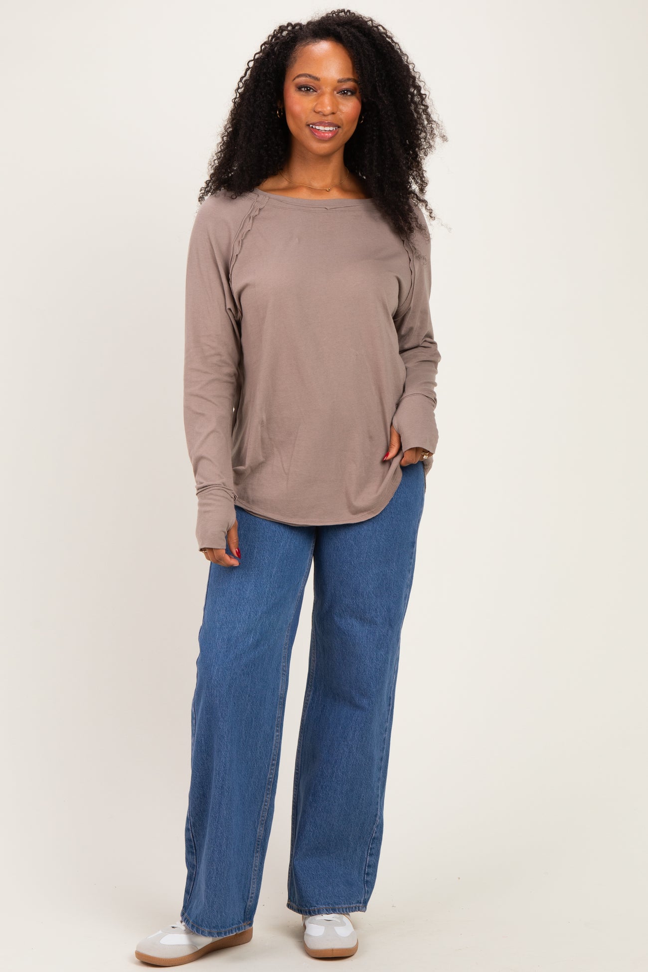 woman wearing a taupe long sleeve top with side ruching and high-waisted blue wide-leg jeans